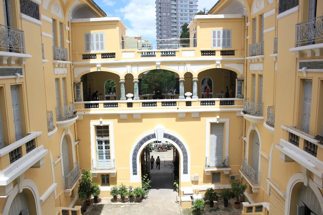Looking down into the courtyard of a yellow colonial building with arched balconies