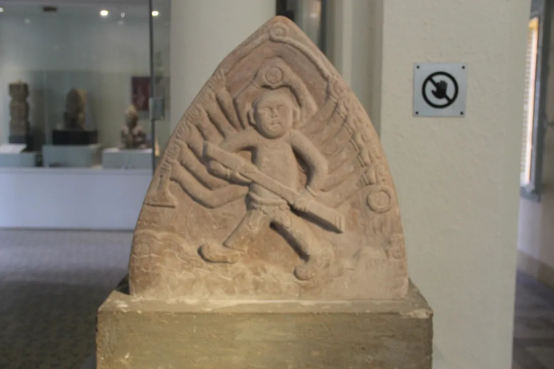A carved stone relief of a many-armed figure holding a weapon