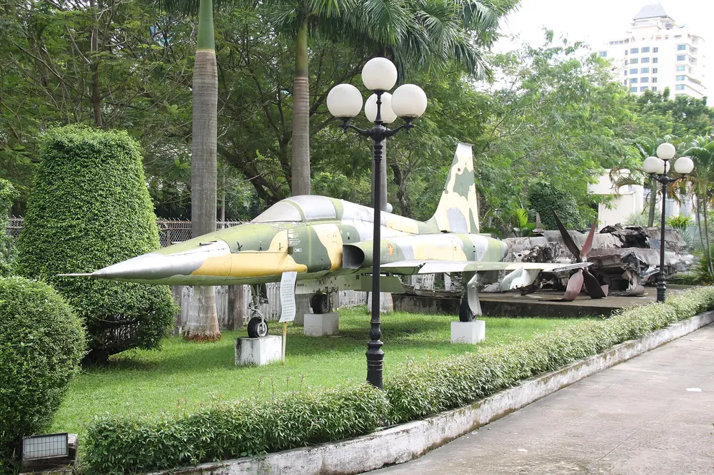 A camouflaged F-5 fighter jet on the lawn in the museum grounds