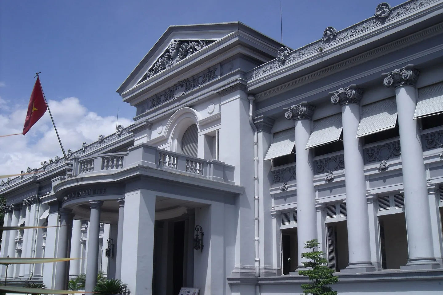 The white colonnaded front of the Ho Chi Minh City Museum under a blue sky