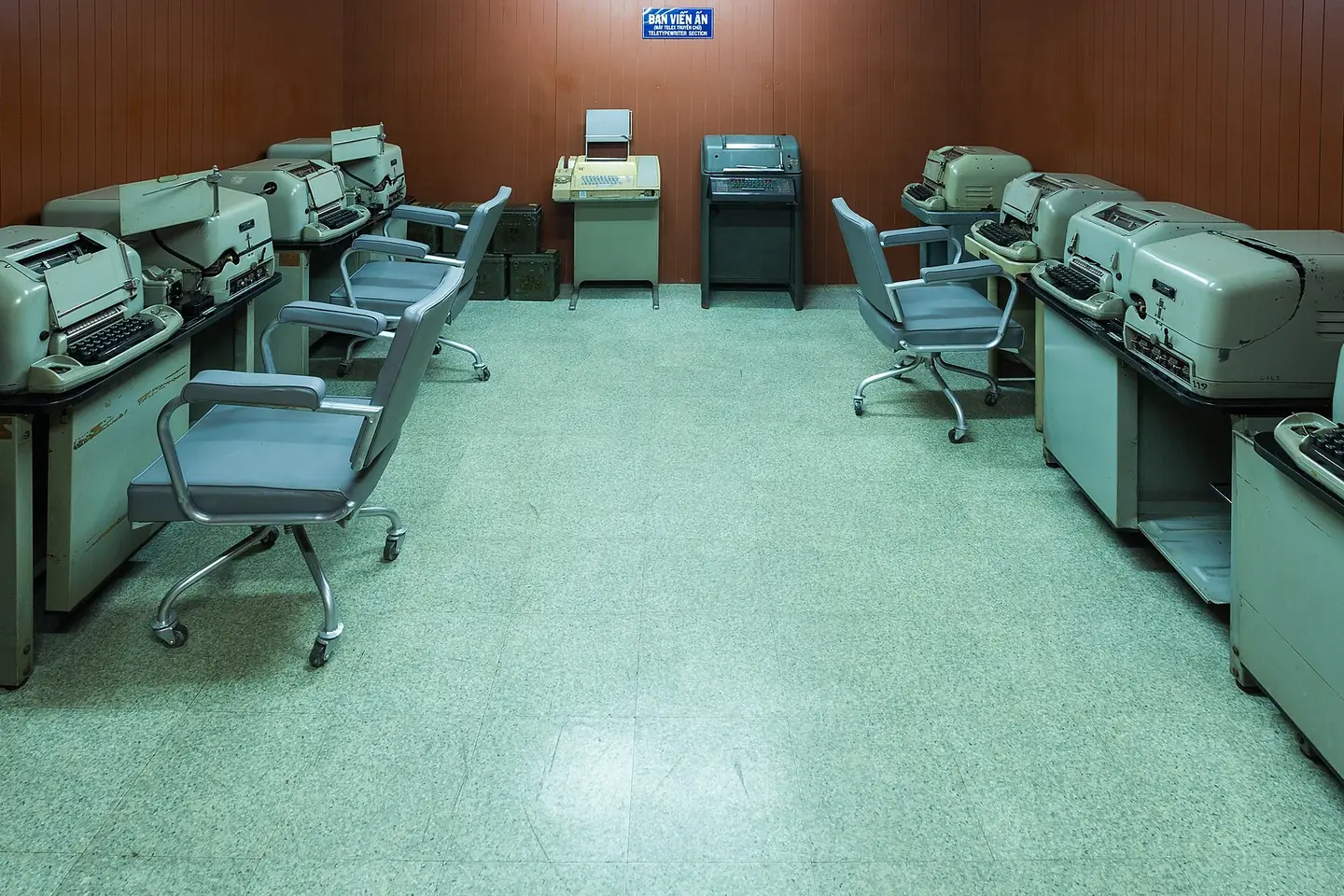 Rows of old teleprinter machines and blue office chairs in a room at the Independence Palace