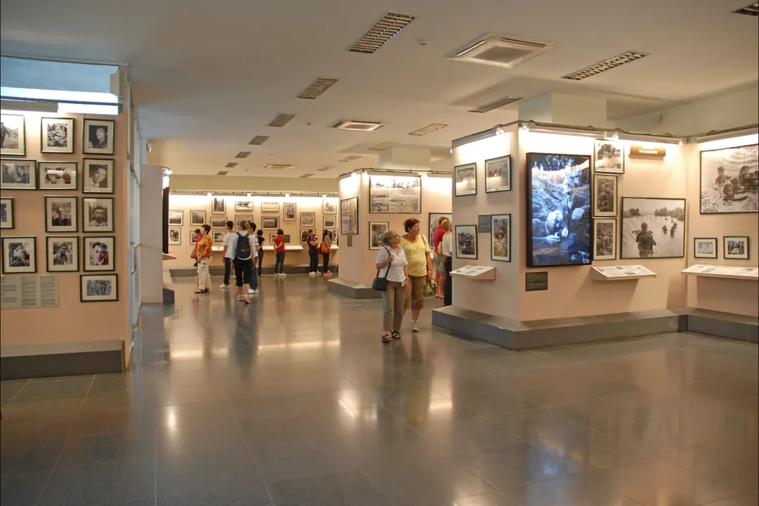 Visitors walking through a bright gallery of framed war photographs