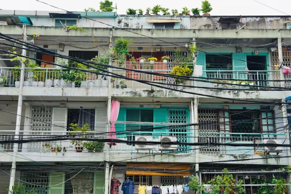 Balconies with plants and teal shutters on an old Saigon apartment block