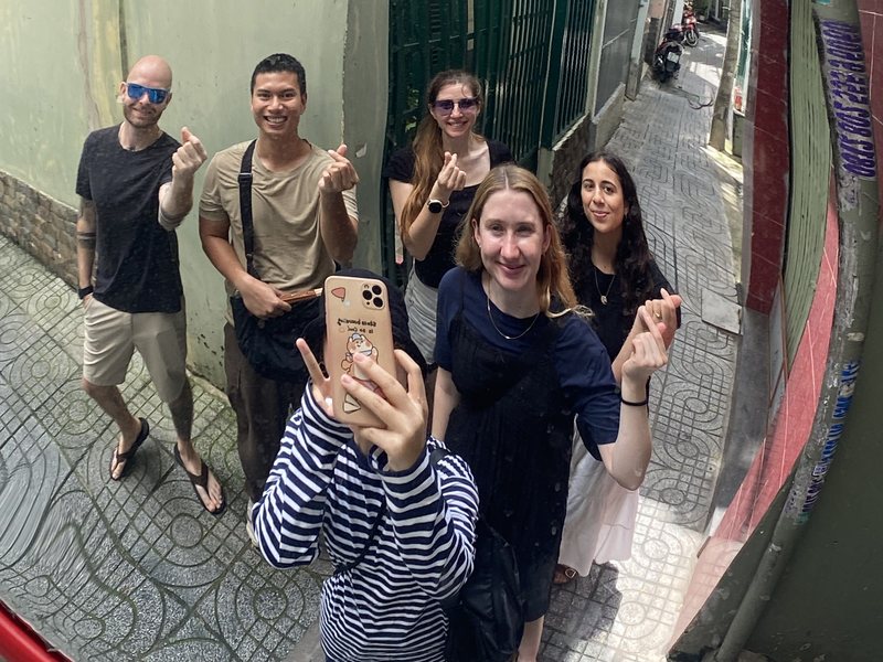 Our guide and guests reflected in a round traffic mirror in a narrow Saigon alley