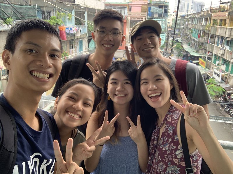 Our guide and five young guests on a walkway above old apartment blocks in Saigon, laundry hanging from the balconies