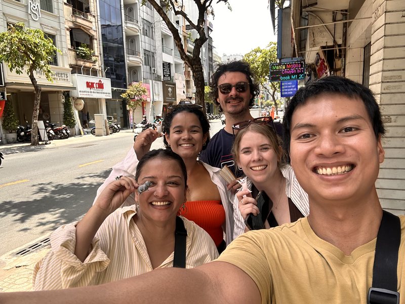 Hieu taking a selfie with four guests on a sunny street in central Saigon