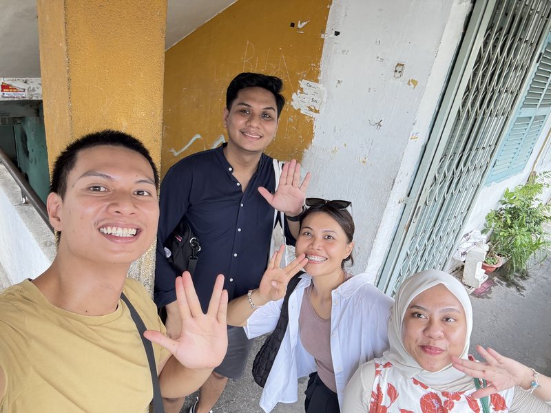 Hieu and three guests in the stairwell of an old apartment building with peeling yellow paint in Saigon