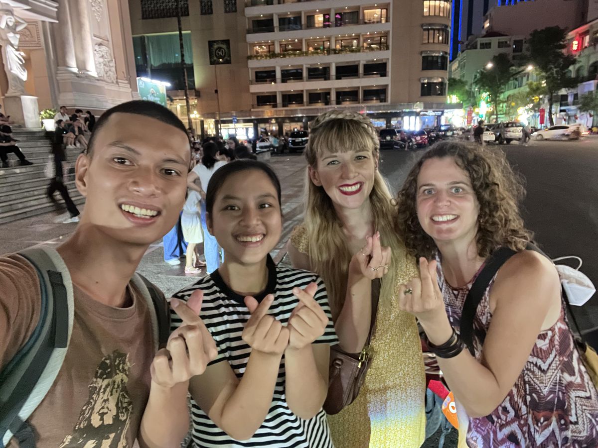 Our guide and guests at night by the steps of the Saigon Opera House, with the Caravelle hotel behind