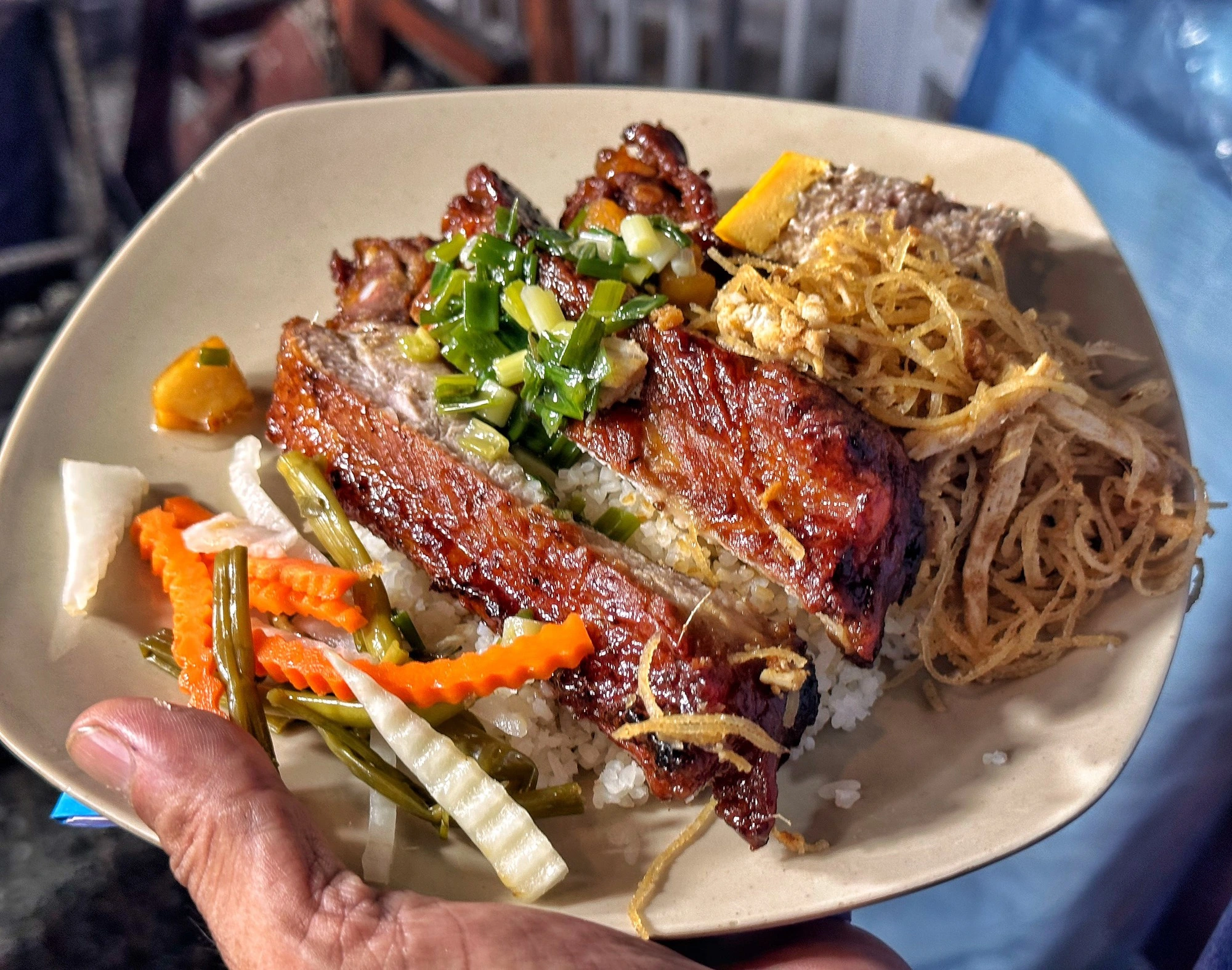 A plate of cơm tấm with grilled pork ribs, shredded pork skin and egg cake in Saigon
