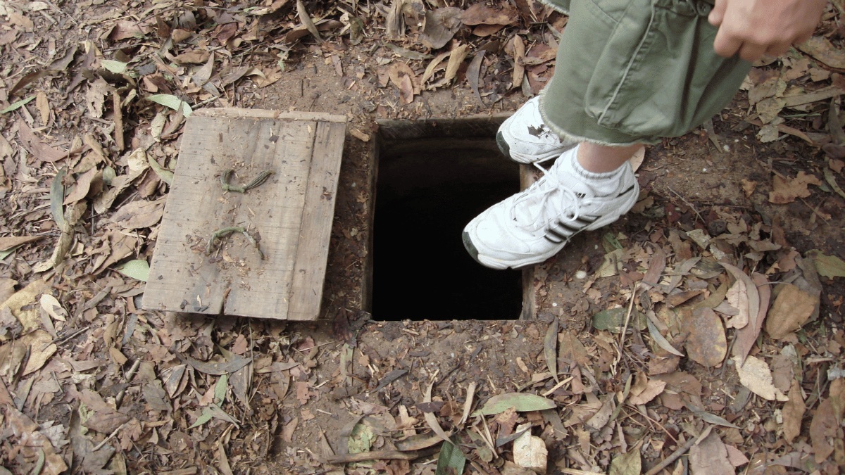 A camouflaged wooden trapdoor open above one of the Cu Chi tunnel entrances
