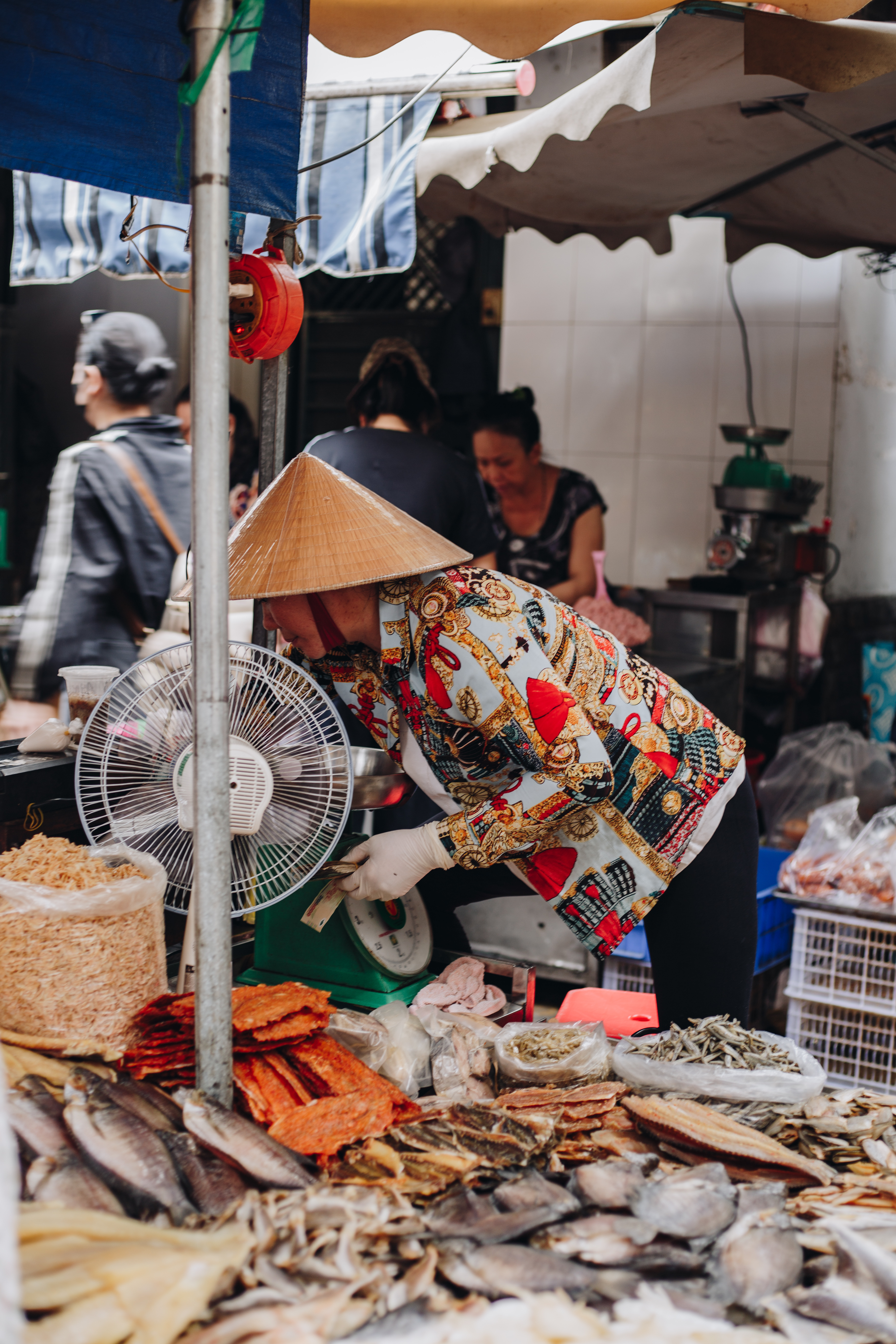 A vendor working her stall in the soft early morning light near a Saigon market