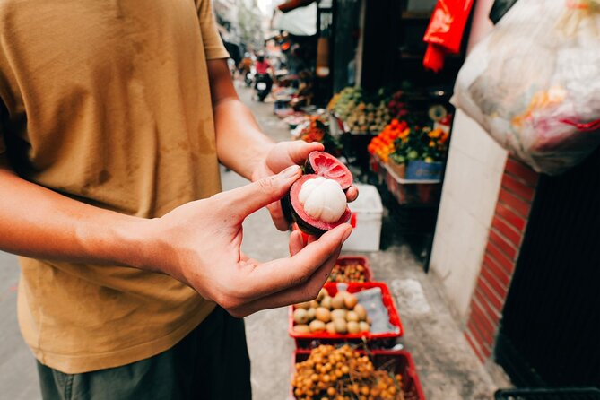 Hands holding an opened mangosteen at a Saigon market