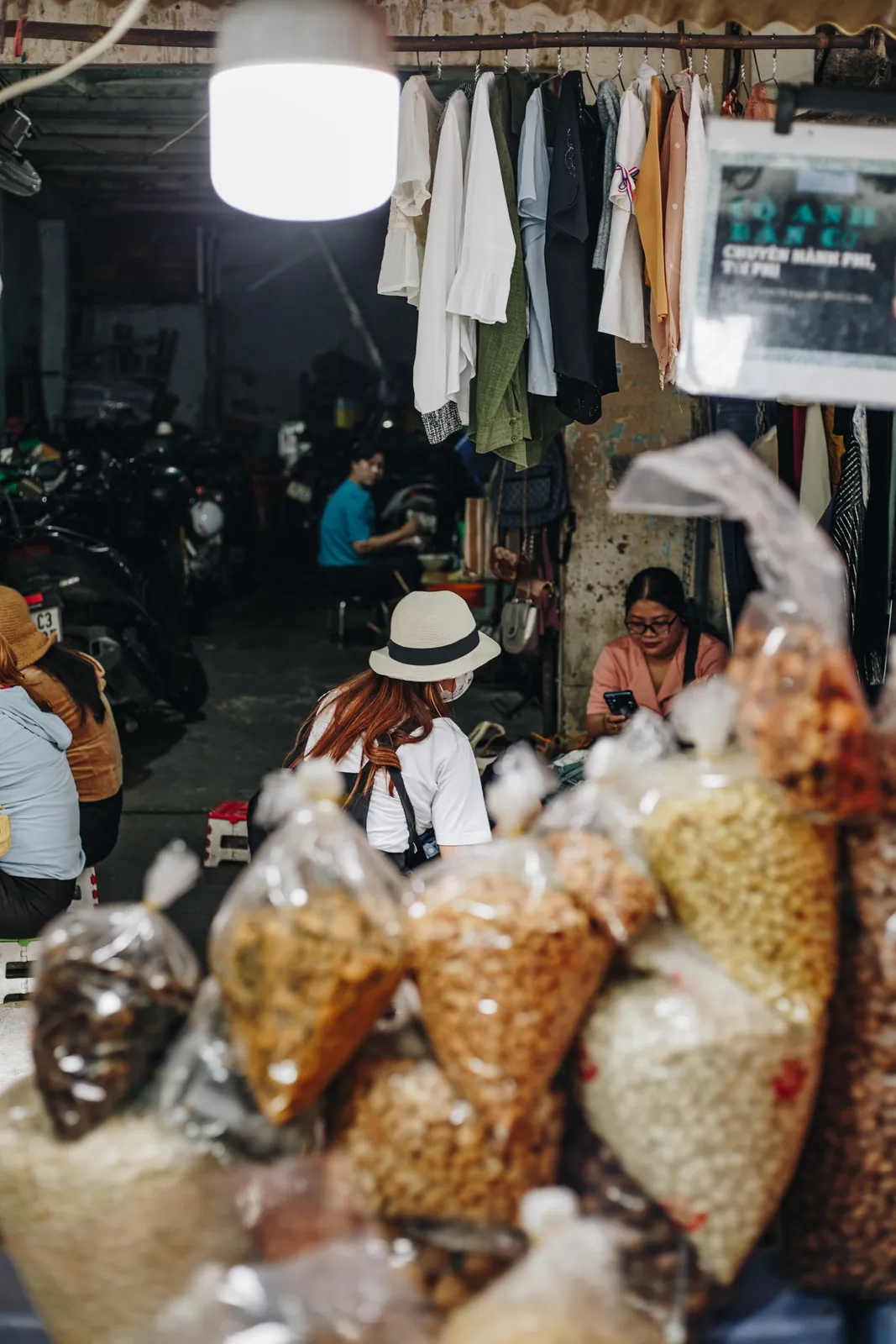 A guest in a hat browsing bags of snacks at a market stall