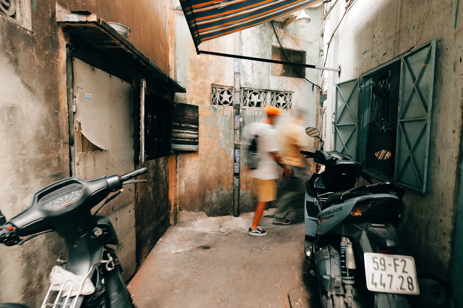 A narrow Saigon alley lined with motorbikes and two people walking through