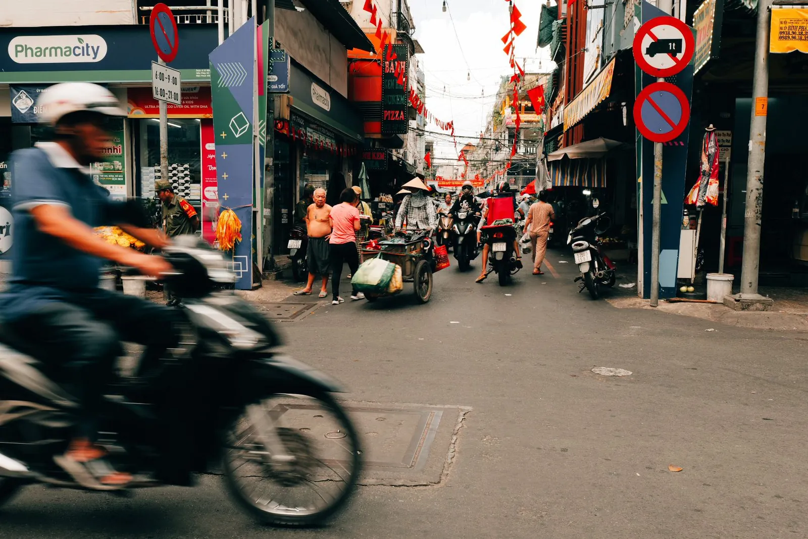 A motorbike rider passing through a busy Saigon market street