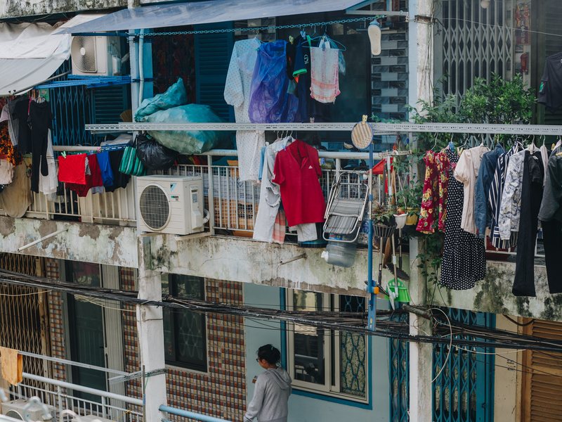 Laundry hanging from the balconies of the old Nguyen Thien Thuat apartment blocks, seen from a walkway with a green railing
