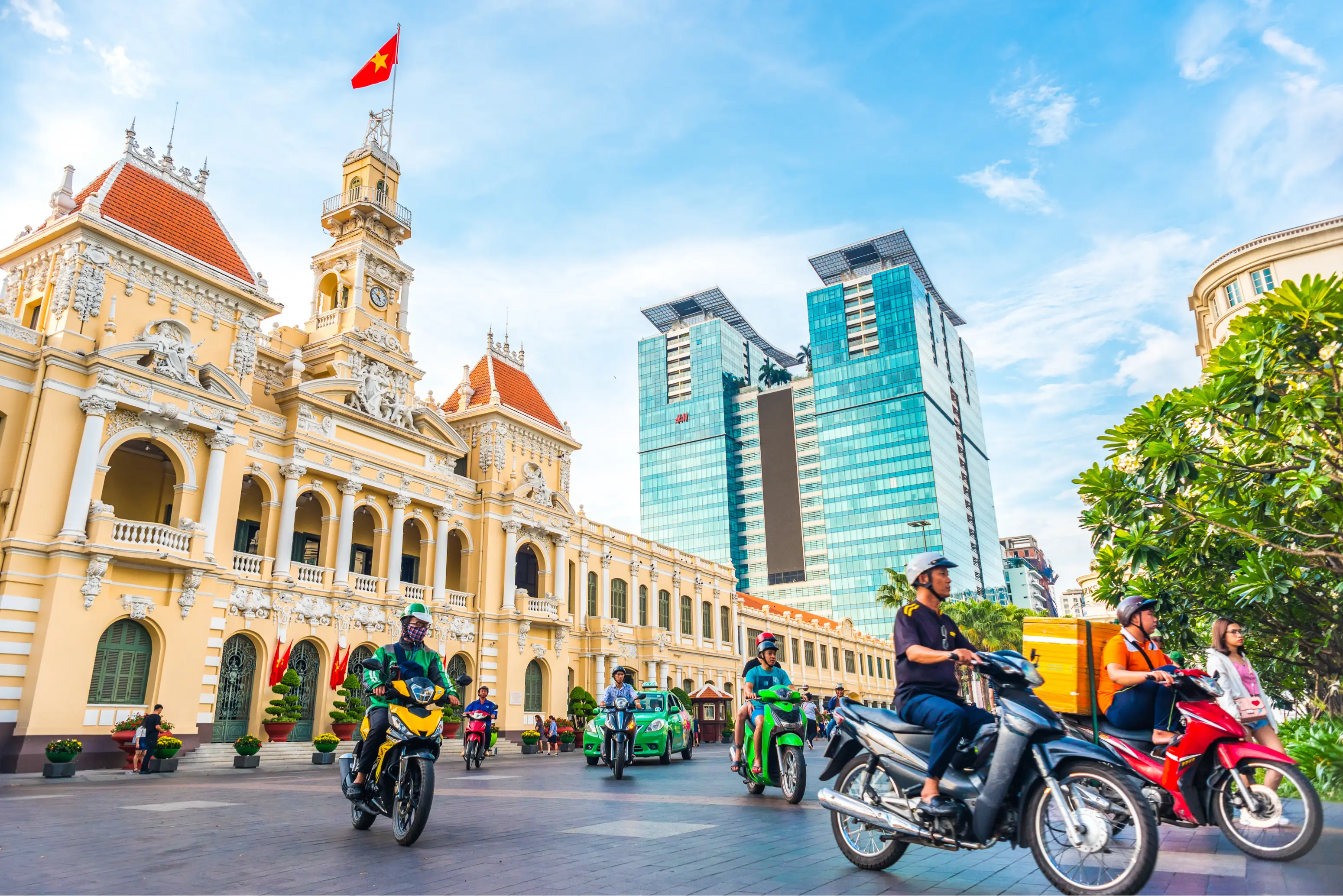 Motorbikes flowing past Saigon City Hall on a sunny morning