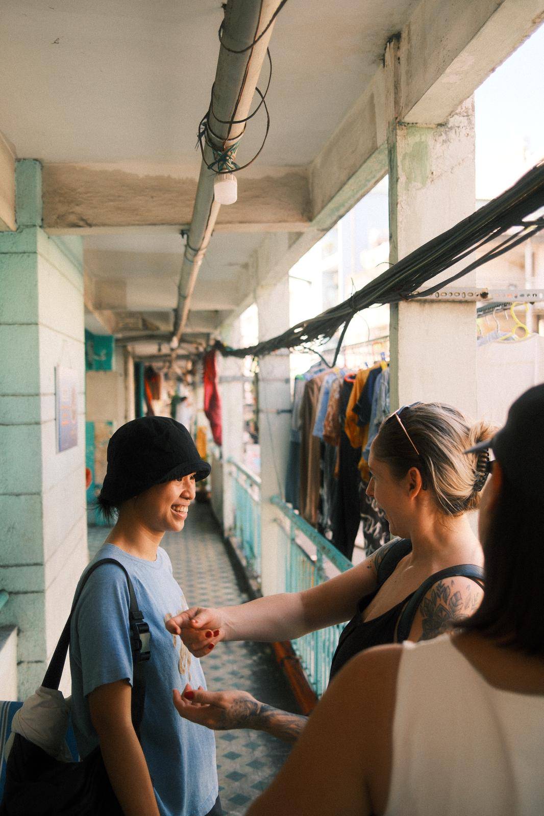 Spring mid-conversation with a guest in a Saigon apartment corridor, afternoon light